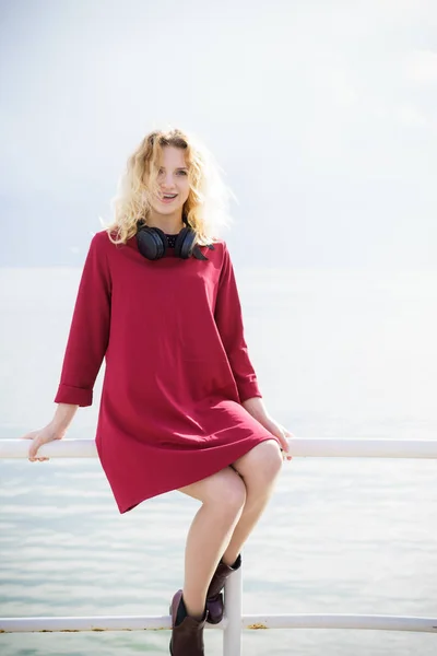Güzel Kırmızı Elbise Giyen Boynunda Pier Deniz Yanında Oturan Kulaklıklar — Stok fotoğraf