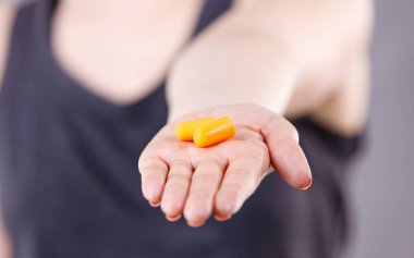 Koruyucu kulak tıkaçları tutan kadın. Gürültüden yüksek sesle kurtulmak, koruma kavramı..