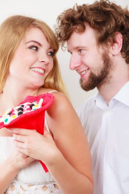 Sevgi dolu çift şeker ile bir buket çiçek grup. Yakışıklı adam ve tutan güzel kadın hediye. İlişki aşk kavramı.