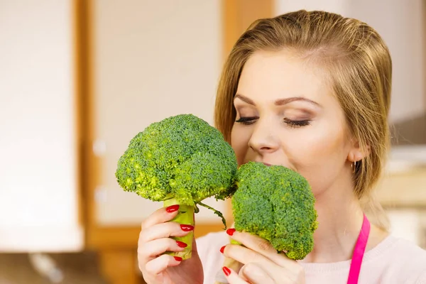 Happy young woman holding raw green vegetable broccoli. Natural organic healthy food concept.