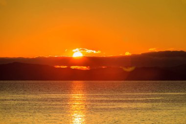 Yunanistan 'da deniz yüzeyinde gün doğumu veya gün batımı manzarası