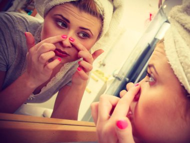 Yansıması hakkında ciddi bir yüz ifadesi, sahip onun kompleksleri ayna düşüncesinde bakarak kadın yüz cilt cilt sivilce sıkma analiz