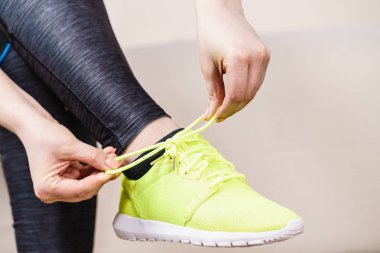 Kadın kanepe kapalı tatbikatların hazırlanıyor oturan spor giyim. Ayakkabılarımı bağlamak