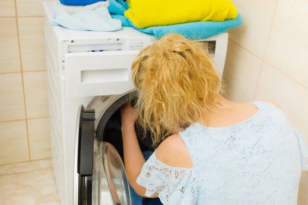Unrecognizable person putting clothes into wasching machine. Laundry objects, household duties concept.