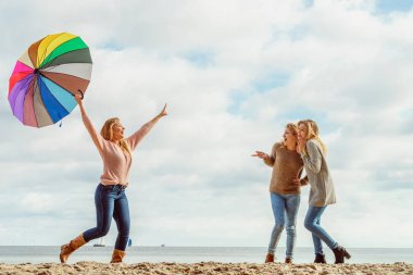 Birlikte harika vakit geçiren üç kadın. Renkli bir şemsiye tutan bir kadın.