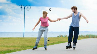Aktif yaşam tarzı ve özgürlük kavramı. Deniz kıyısında paten süren genç ve zinde bir çift, kadın ve erkek birlikte vakit geçiriyorlar..
