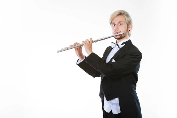 Classical music study concept. Male flutist musician performer playing flute. Young elegant man wearing tailcoat holds instrument
