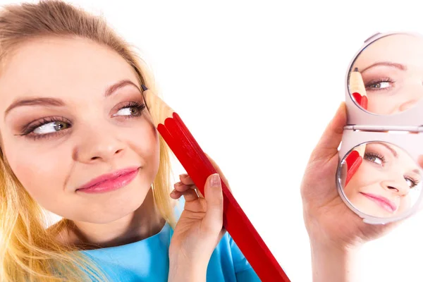 Funny silly woman trying to paint her eyebrows using big huge oversized regular student pencil. Make up fun concept.