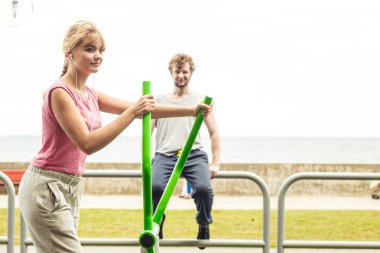 Aktif kadın eliptik eğitmen makine ve müzik adam egzersiz. Açık spor salonunda egzersiz eğitim elbiseli sportif kız uygun. Spor fitness ve sağlıklı yaşam konsepti.