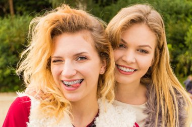 Sıcak sonbahar havasında şık kıyafetler giyen iki şık kadın boş zamanlarını dışarıda geçiriyorlar.