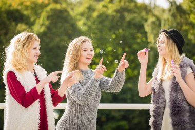 Tatil eğlencesi, arkadaşlık konsepti. Kadın arkadaşlar dışarıda sabun köpüğü üflerken eğleniyorlar..