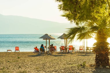 Su veren kimse deniz kenarında ile gölge şezlonglar, kumsalda güneş şemsiye.