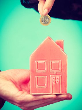 Gelecek planları için tasarruf. Elleriyle kırmızı küçük ev kumbara ve gümüş sikke. Aile ev daha iyi yaşam için para bel.