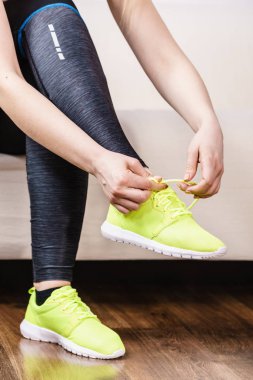 Kadın kanepe kapalı tatbikatların hazırlanıyor oturan spor giyim. Ayakkabılarımı bağlamak