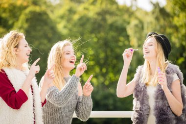 Tatil eğlencesi, arkadaşlık konsepti. Kadın arkadaşlar dışarıda sabun köpüğü üflerken eğleniyorlar..
