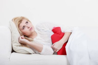 Ağrılı dönemler ve menstrüel kramp sorunları kavramı. Mide sahip kadın biraz rahatlama hissetmeye sıcak su şişesi tutan çok iyi duygu cofa yalan krampları