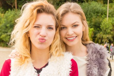 Sıcak sonbahar havasında şık kıyafetler giyen iki şık kadın boş zamanlarını dışarıda geçiriyorlar.