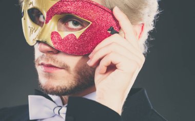 Tatil, insanlar ve kutlama kavramı. Takım elbise beyaz gömlek papyon ve karnaval Venedik Maske, karanlık giyen zarif genç adam.