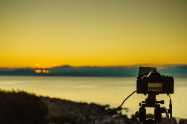 Professional camera taking picture film video of sunrise over sea surface, Greece Peloponnese. clipart