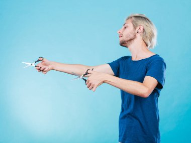 Saç kesimi saç bakım konsepti. Tutkulu erkek kuaför elinde makasla iş aletlerini normal ve seyrelten makasları gösteriyor.
