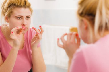 Yansıması hakkında ciddi bir yüz ifadesi, sahip onun kompleksleri ayna düşüncesinde bakarak kadın yüz cilt cilt analizi.