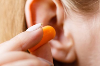 Yüksek sesle yerinde gürültü kurtulmak onun kulaklarına kadın koyarak kulak tıkacı.