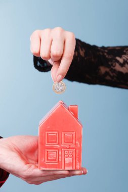 Gelecek planları için tasarruf. Elleriyle kırmızı küçük ev kumbara ve gümüş sikke. Aile ev daha iyi yaşam için para bel.