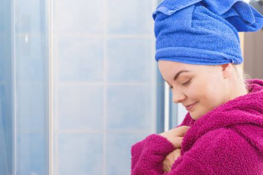 Banyoda duş aldıktan sonra havluyla ve bornozla kendini rahat hisseden genç bir kadın.