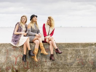 Üç modaya uygun kadın şık kıyafetler giyiyorlar. Tarz, moda, arkadaşlık konsepti.