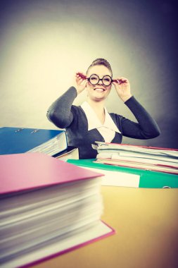 Mutluluk ve memnuniyet çalışmasını. Genç olumlu mutlu sarışın muhasebeci iş başında. Renkli ciltler yığınları çevrili güzel kadın.