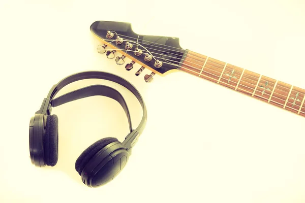 Equipment of musician. Electric electro black guitar string intrument and big headphones lying ready to use.