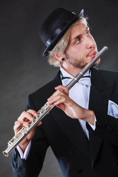 古典的な音楽 情熱と趣味の概念 エレガントな黒いソフト帽の帽子をかぶってフルート演奏ミュージシャン男を服を着せた 暗い灰色の背景で撮影スタジオ — ストック写真