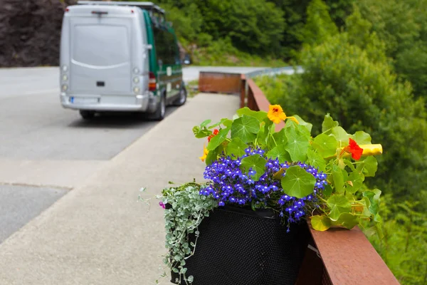 Camper van with storage bag on parking area at Svandalsfossen waterfall in Norway. Flowers decoration with old bicycle. National tourist Ryfylke route.