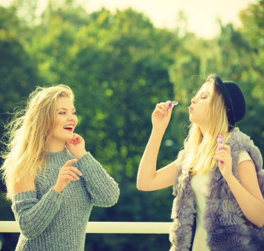 Tatil eğlencesi, arkadaşlık konsepti. Kadın arkadaşlar dışarıda sabun köpüğü üflerken eğleniyorlar..