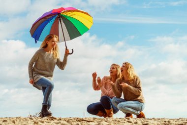 Birlikte harika vakit geçiren üç kadın. Renkli bir şemsiye tutan bir kadın.