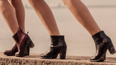 Dışarıda şık ayakkabılar giyen tanınmayan üç modaya uygun kadın. Botlar sonbahar ve kış için mükemmel.