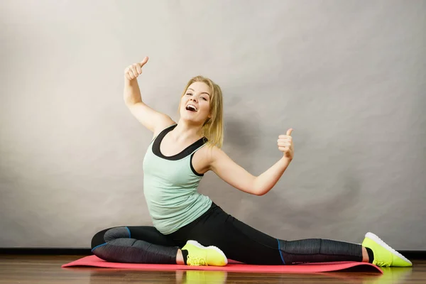 若いブロンドの女性スポーツウェア木製の床の屋内ストレッチ足に座っている 家でのトレーニング フィット感と健康 — ストック写真
