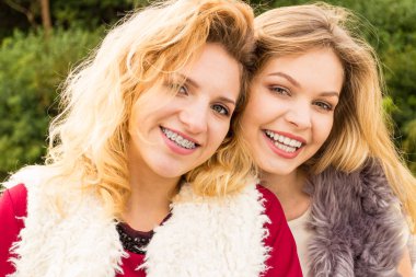 Sıcak sonbahar havasında şık kıyafetler giyen iki şık kadın boş zamanlarını dışarıda geçiriyorlar.