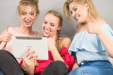 Eğleniyor koltukta oturan kadınlar akıllı dijital pc tablet modern cihaz kullanarak internette sörf