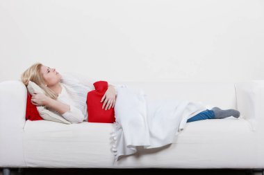 Ağrılı dönemler ve menstrüel kramp sorunları kavramı. Mide sahip kadın biraz rahatlama hissetmeye sıcak su şişesi tutan çok iyi duygu cofa yalan krampları