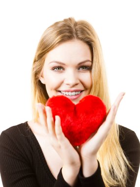 Küçük kırmızı kalp şeklinde yumuşacık yastık tutan romantik bir kadın. Sevgililer Günü hediyesi..