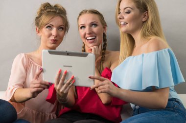 Eğleniyor koltukta oturan kadınlar akıllı dijital pc tablet modern cihaz kullanarak internette sörf