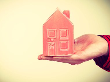 İlk düz daire. İleri adım konsepti. Erkek el ele tutuşmuş küçük kırmızı bir ev. Büyüme fikri olan yarı vücut adam..