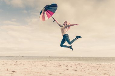 Mutluluk, havanın, duygu büyük kavram tadını. Deniz, güneşli ve açık mavi gökyüzü yakınındaki plajda renkli şemsiye ile atlama kadın