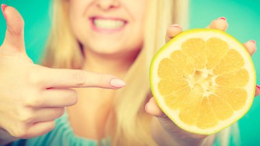 Sarı greyfurt yarısı narenciye meyve elinde tutan, parmakla işaret, sağlıklı beslenme, yeşil tavsiye kadın gülümseyen kız. Diyet kaybetme ağırlık kavramı.