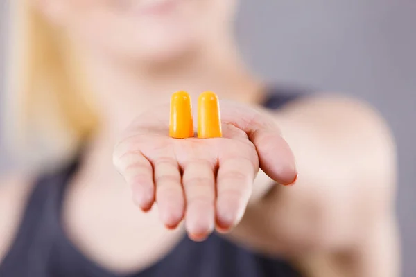 Woman holding protective ear plugs. Getting rid on noise in loud place, hearing protection concept.