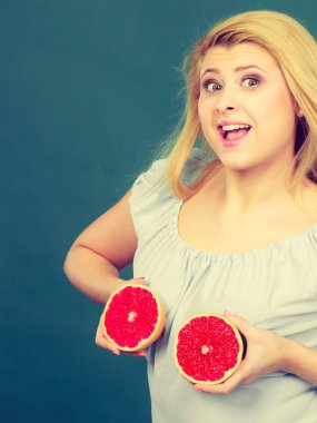 Eğleniyor, yeşil kırmızı greyfurt iki halfs narenciye meyve meme üzerinde tutan kadın komik kız. Sağlıklı bir diyet yemek.