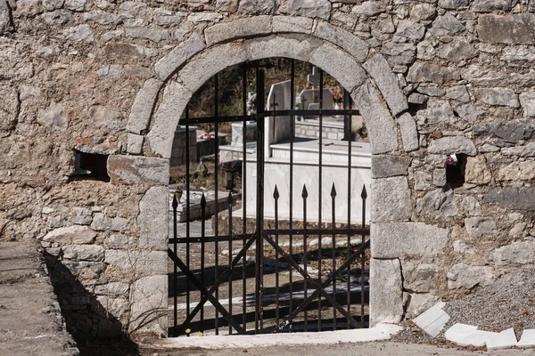 Entrance to the old cemetery, made of rocks, bricks and metal bars.