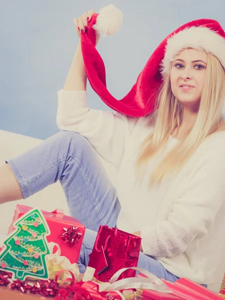 季節のコンセプト ブロンドの女性はソファに座って サンタの帽子をかぶって 暖かいクリスマスの雰囲気を楽しんで — ストック写真