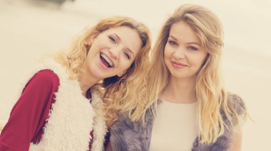 Sıcak sonbahar havasında şık kıyafetler giyen iki şık kadın boş zamanlarını dışarıda geçiriyorlar.